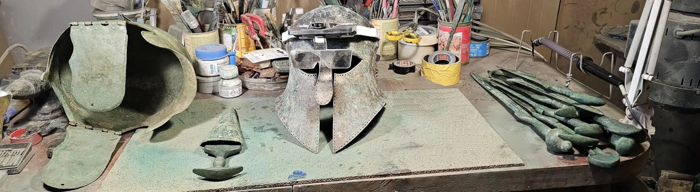 Conservator’s workbench with ancient bronze helmets and arms during conservation